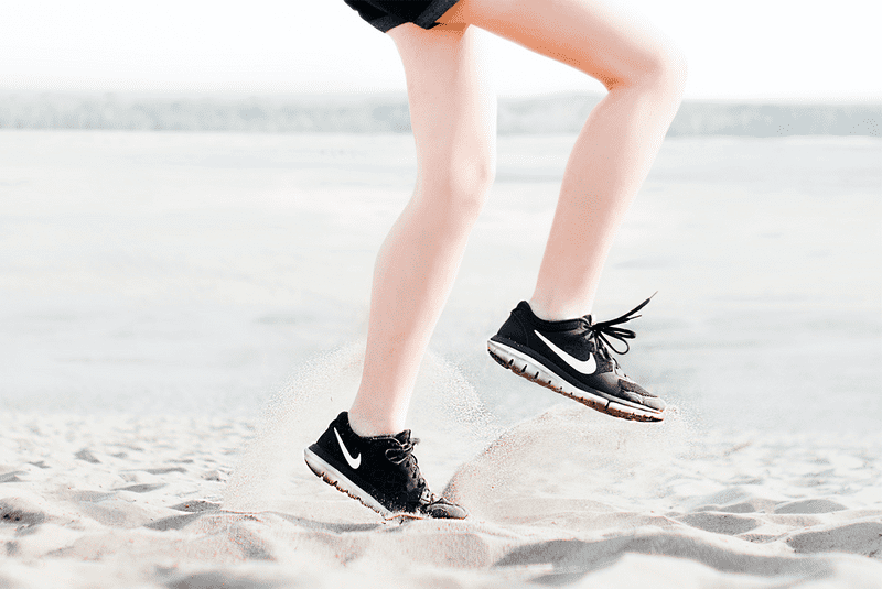 woman's legs running on sand